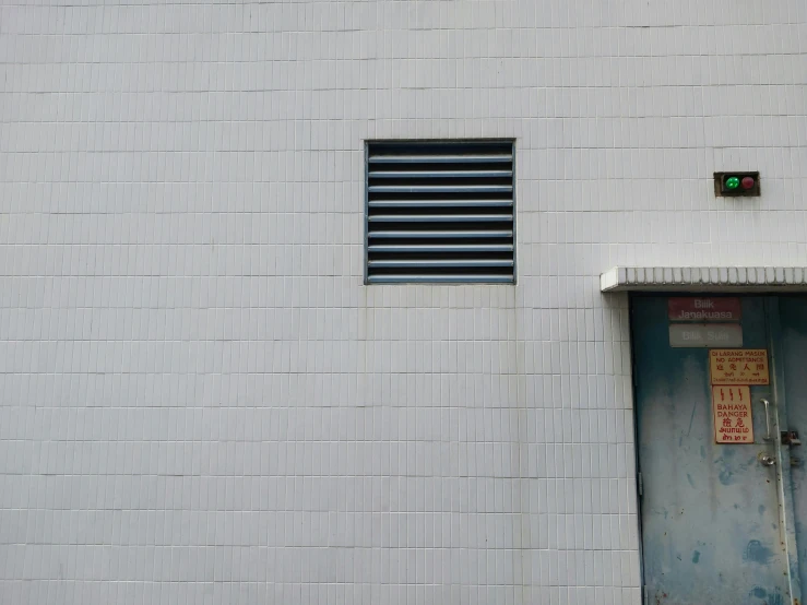 a gray door with a red on stands by a brick wall