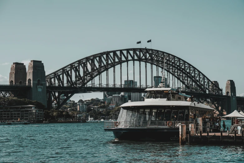 a boat with passengers passes under the sydney harbour bridge