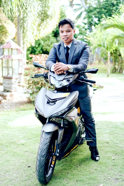 a man on a motorcycle in a suit posing for a picture