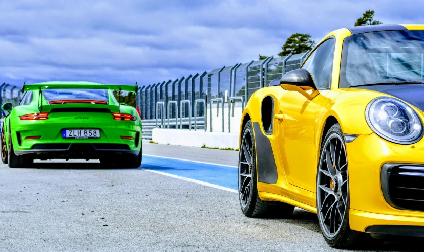 two yellow cars driving on the road with one green car