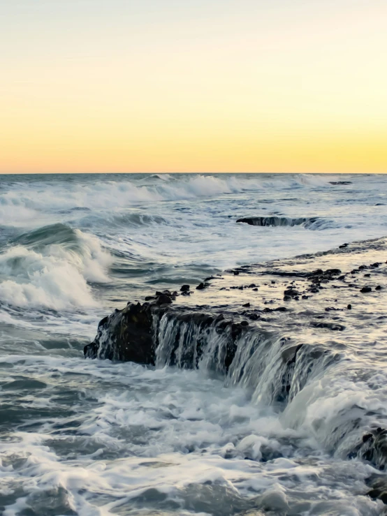 the tide is breaking on some rocks on the beach