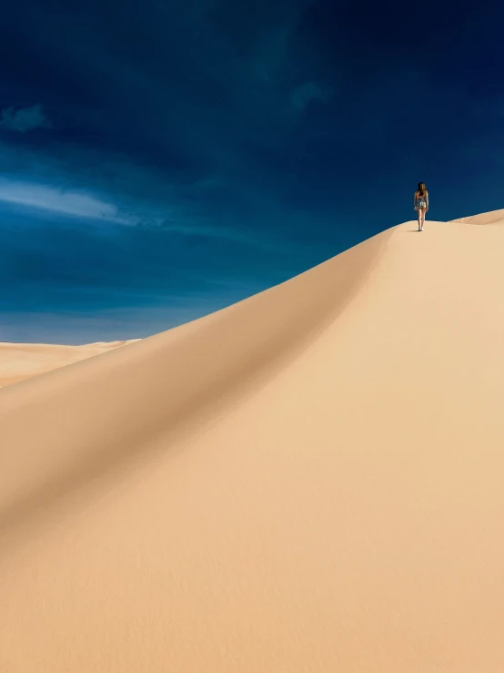 two people on a dune under the blue sky