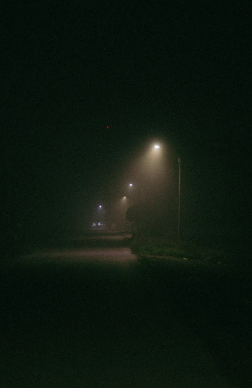 a foggy road at night with street lamps