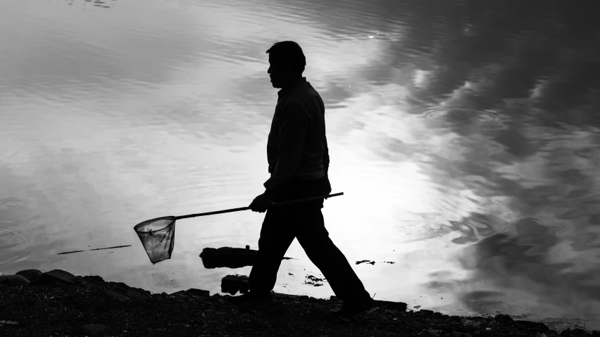 a person standing next to a body of water with a fishing net