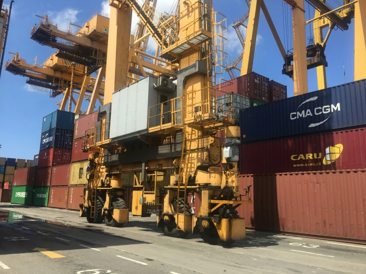 a yellow crane stands next to some large shipping containers