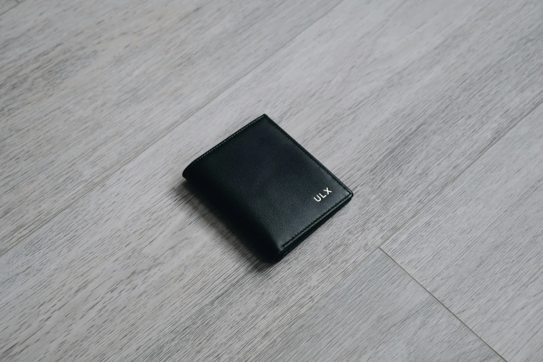 a black wallet sits on top of a wooden floor