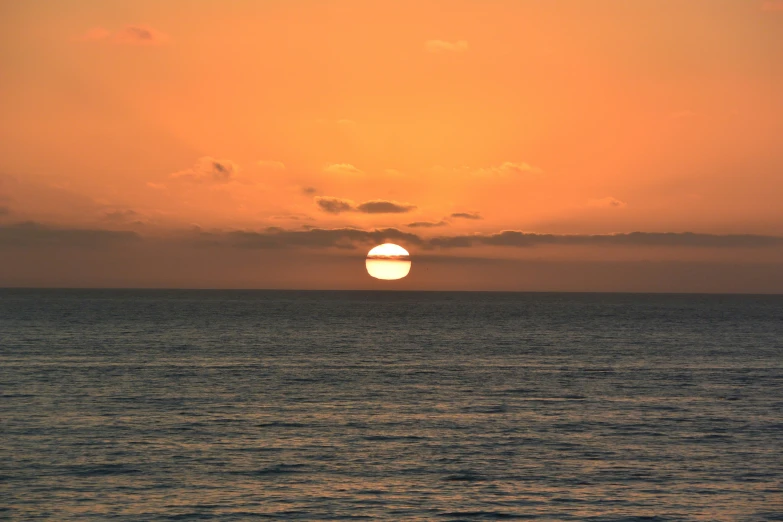 the sun setting behind the clouds over the ocean