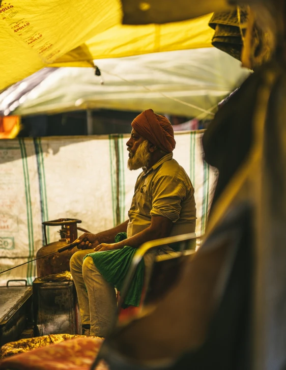 a man sits outside wearing a red turban and yellow clothes