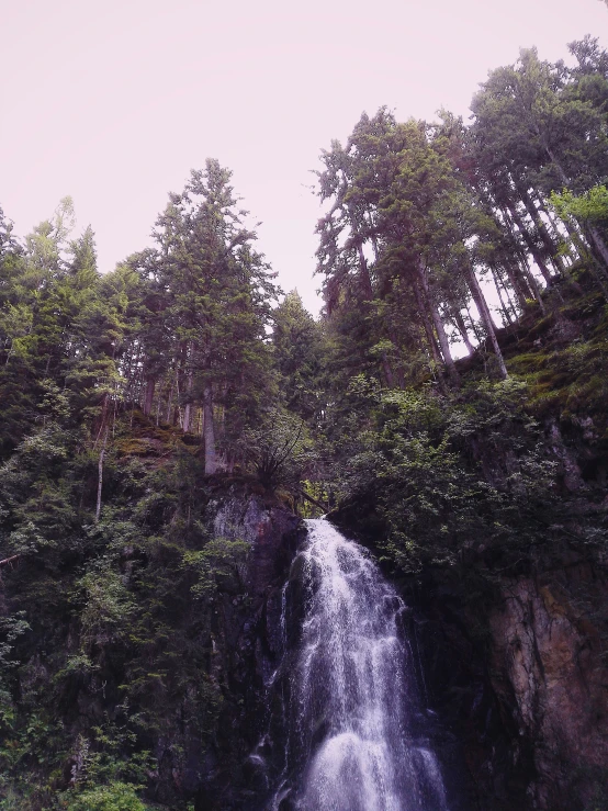 a man in a kayak at the base of a waterfall