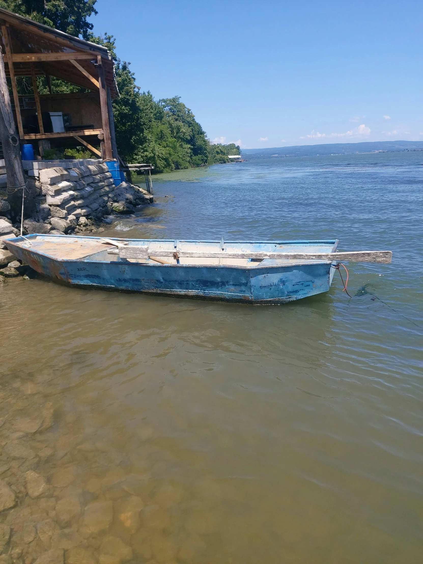 a small blue boat in shallow water by an old dock