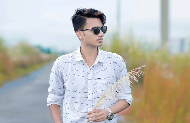 a young man with sunglasses holding a stick