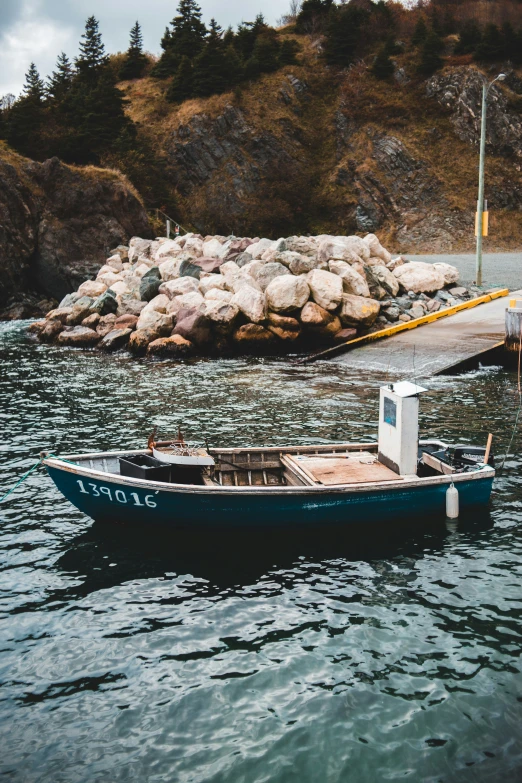 a small blue boat is tied up at the dock