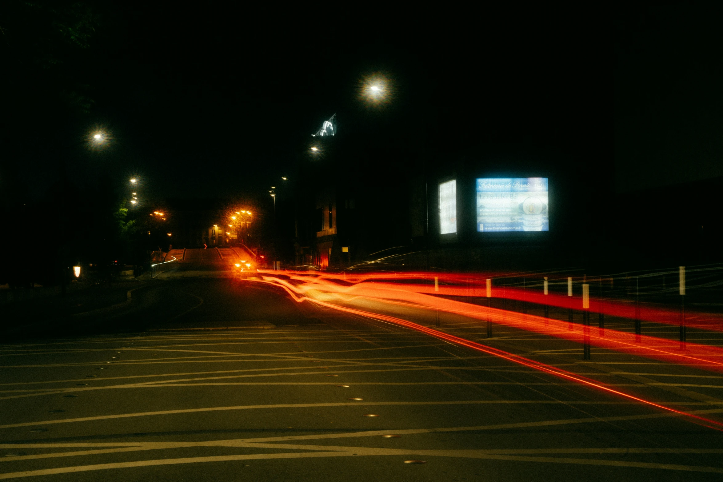 an empty city street at night with motion blurs on the pavement