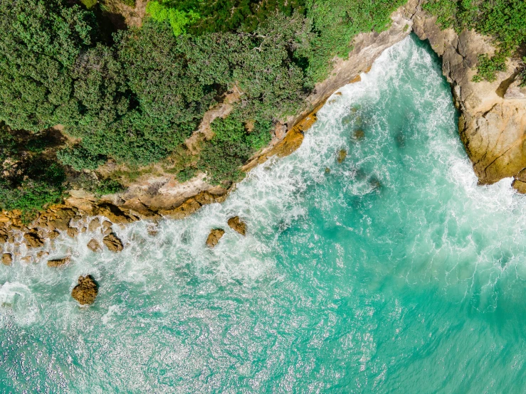 water that is crashing into shore near a cliff