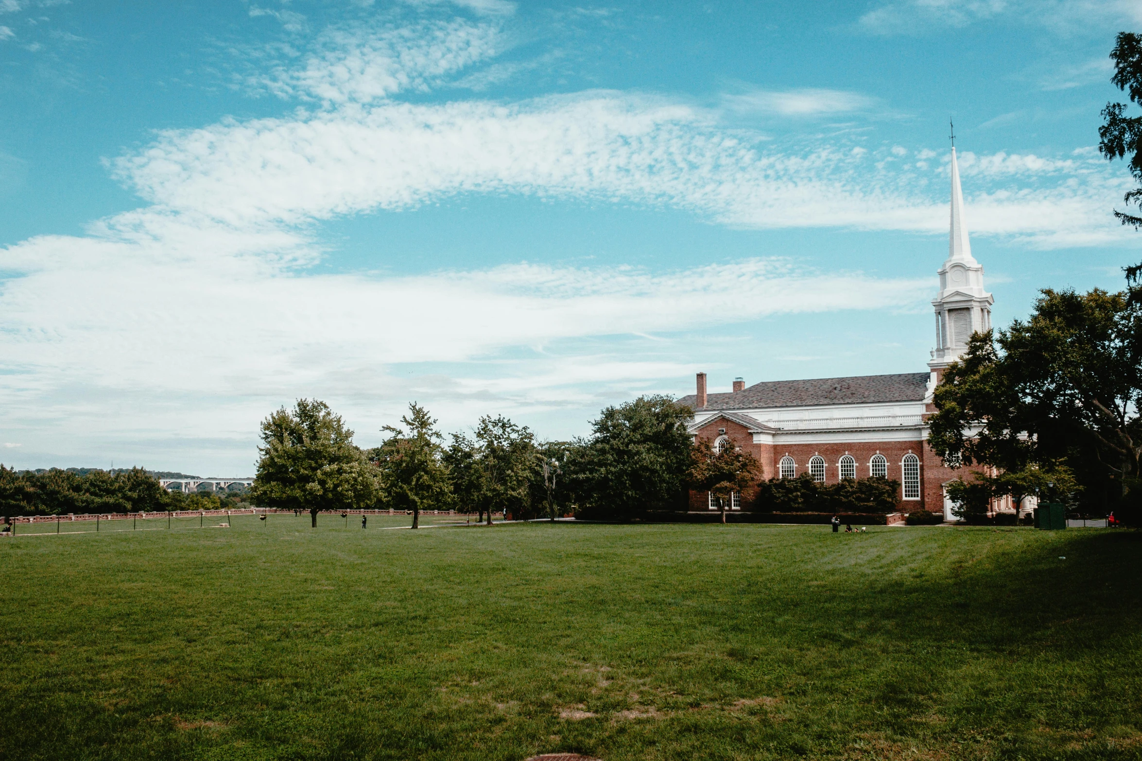 large grassy field with buildings and trees in the distance