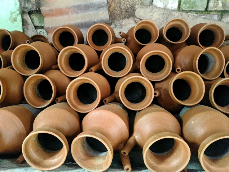 some old brown pots are stacked next to each other
