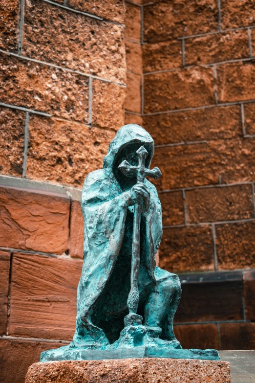 a small bronze statue of a person on a block wall