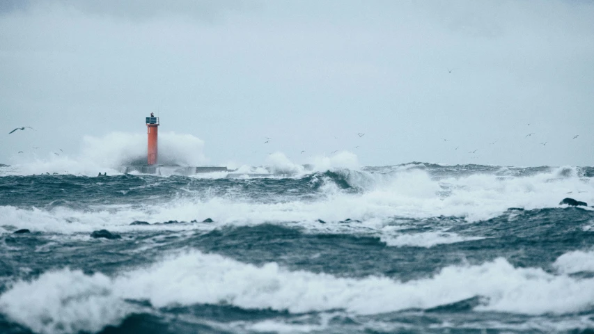 a light house with ocean waves and a bird flying