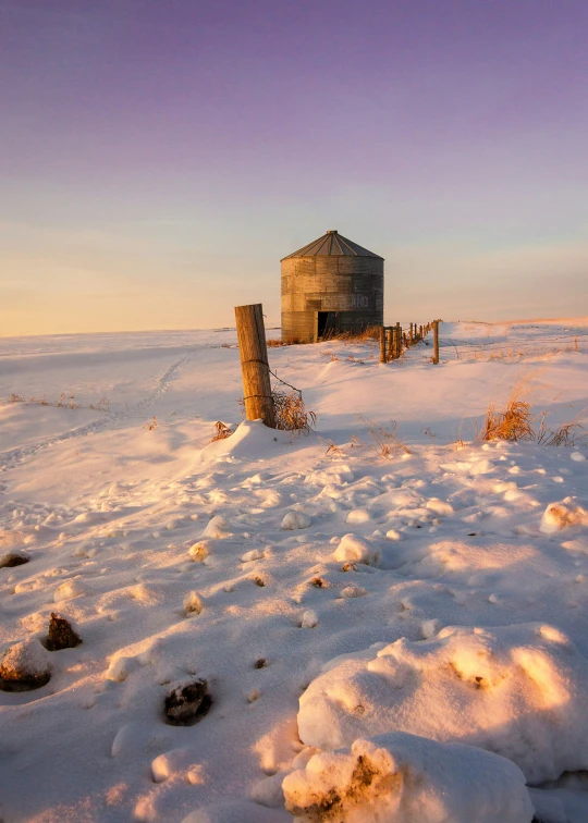 the snow covered ground has a old building in it