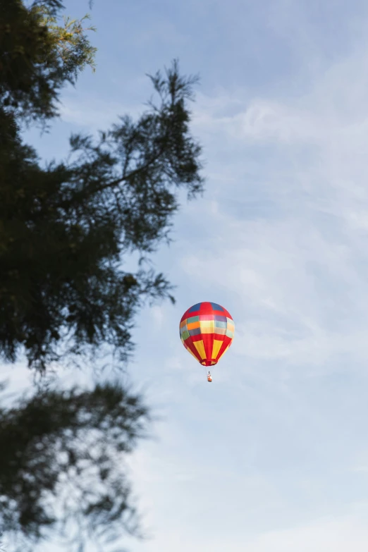 a big balloon flying through a blue sky next to trees