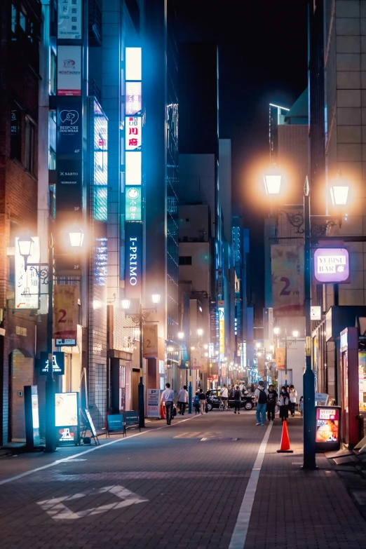 a group of people walking down a street at night