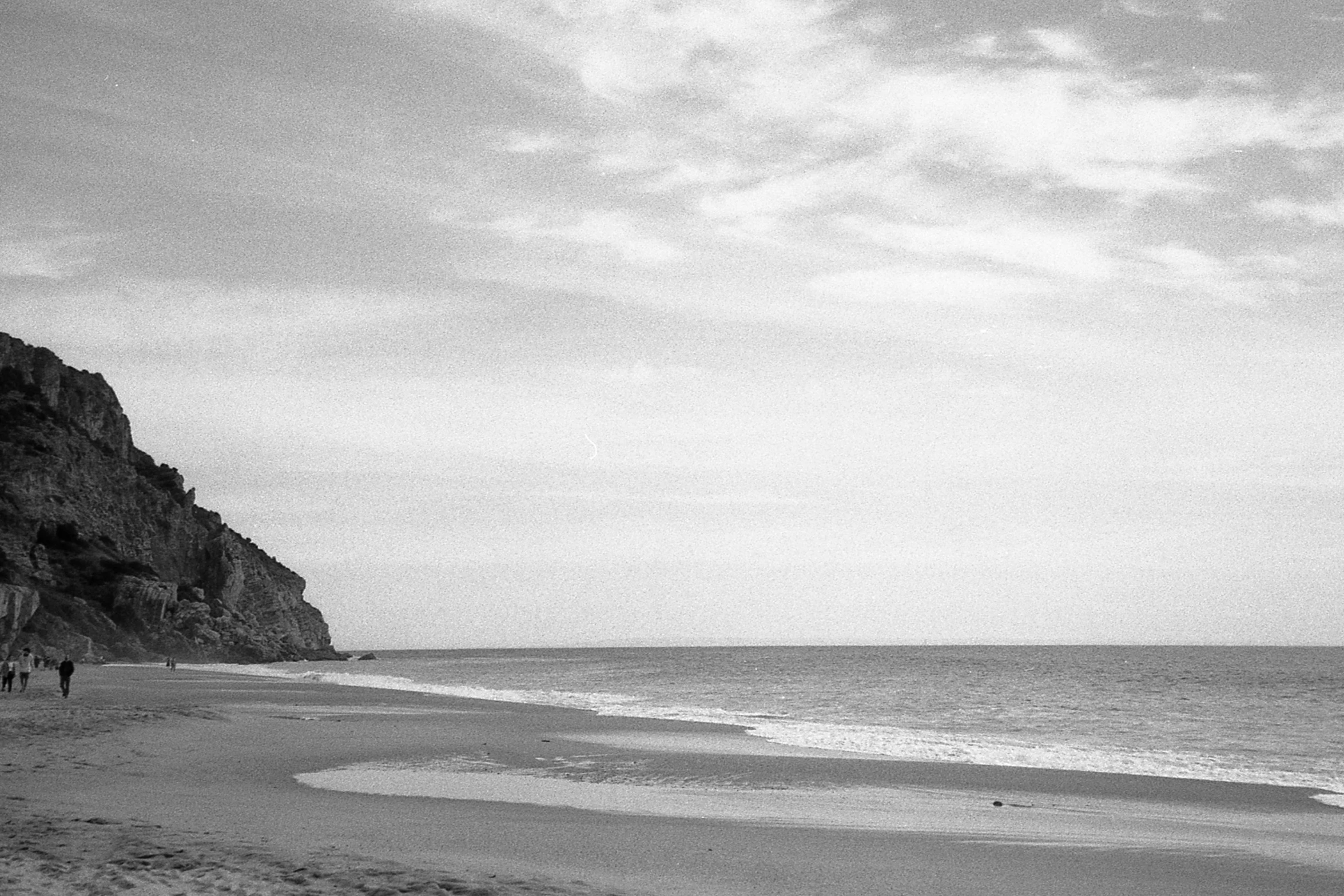 a beach with people walking on the shoreline