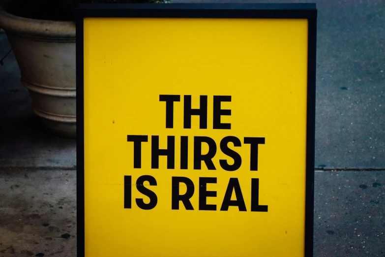 a sign that reads the thirst is real on a sidewalk