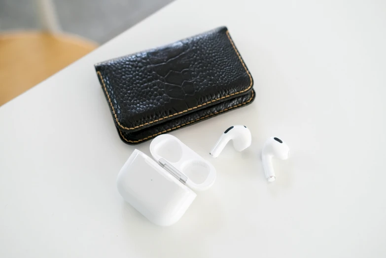 an apple airpods and a wallet on a table