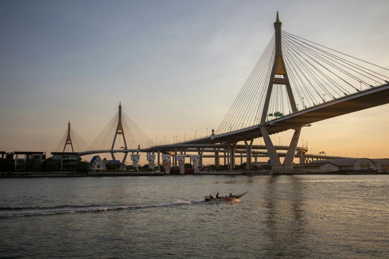 a person on a small boat paddling past a bridge