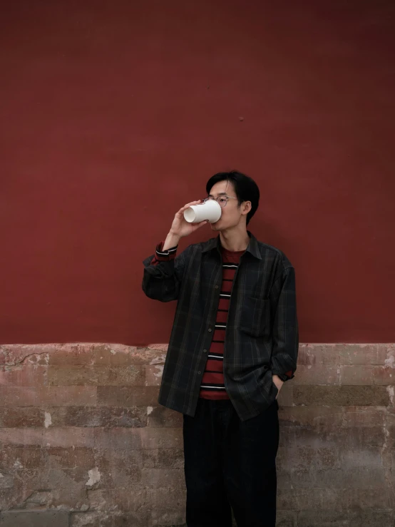 a man in a long shirt drinking from a mug