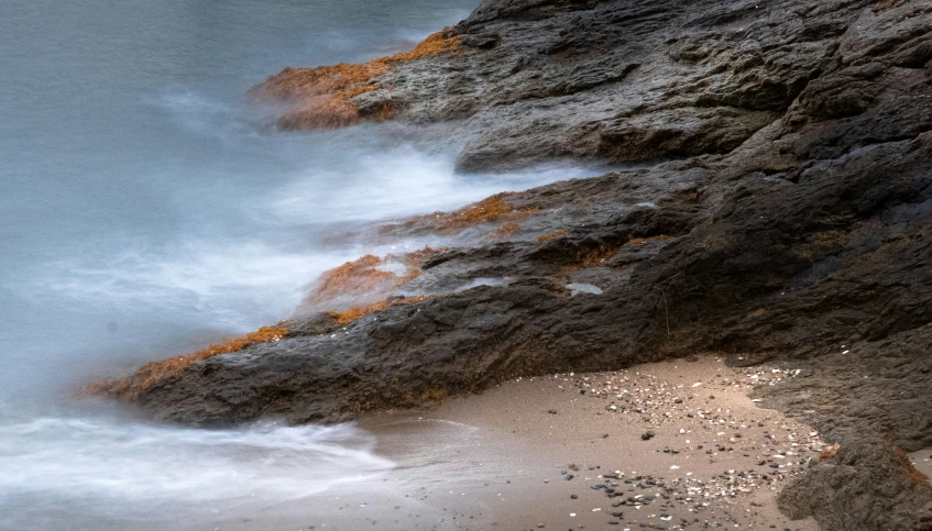 a rocky cliff next to a body of water