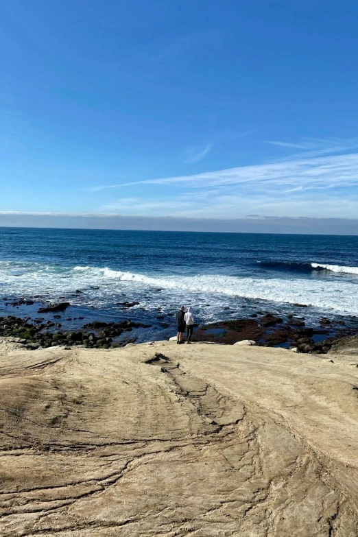 people on sand near beach with ocean and blue sky