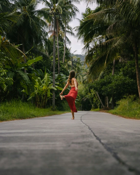 a girl in red doing yoga on the road with palm trees