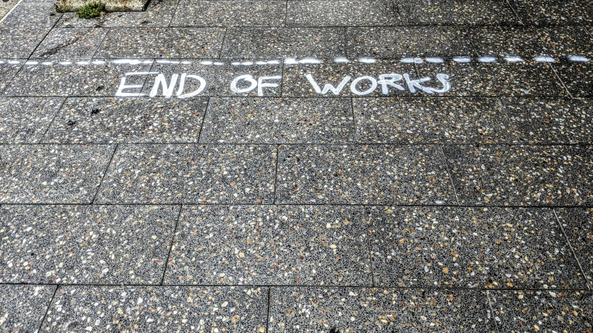 white writing on asphalt reads end of work