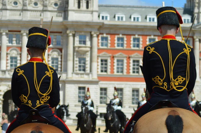 two soldiers dressed in military uniforms riding horses outside the castle