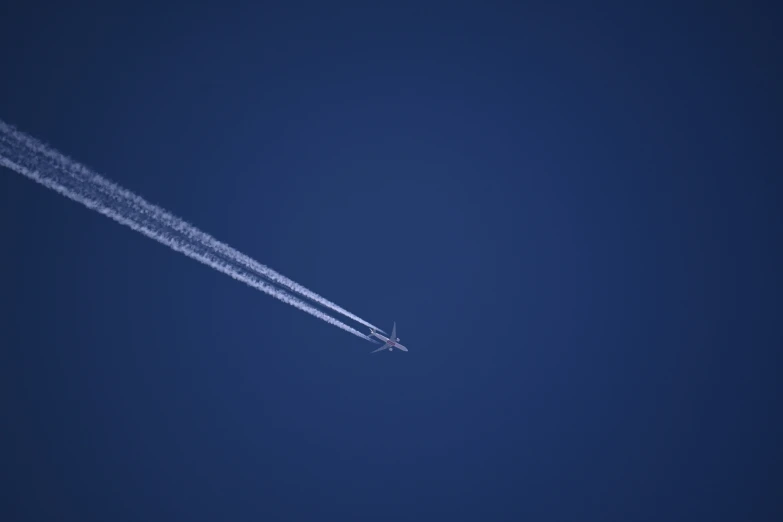 a plane flying in the blue sky and leaving a trails trail behind