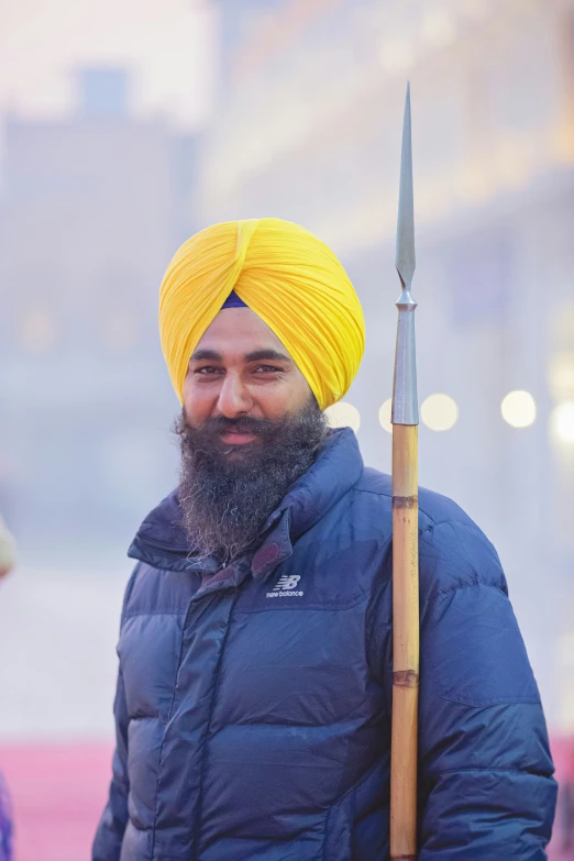 an indian man in a yellow turban holding a large stick