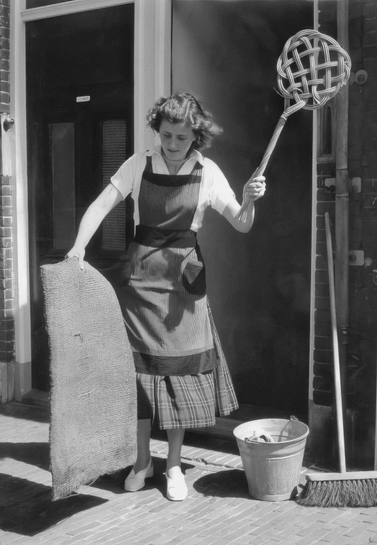 an old black and white po shows a woman holding soing in one hand, a basket and a large object on the other