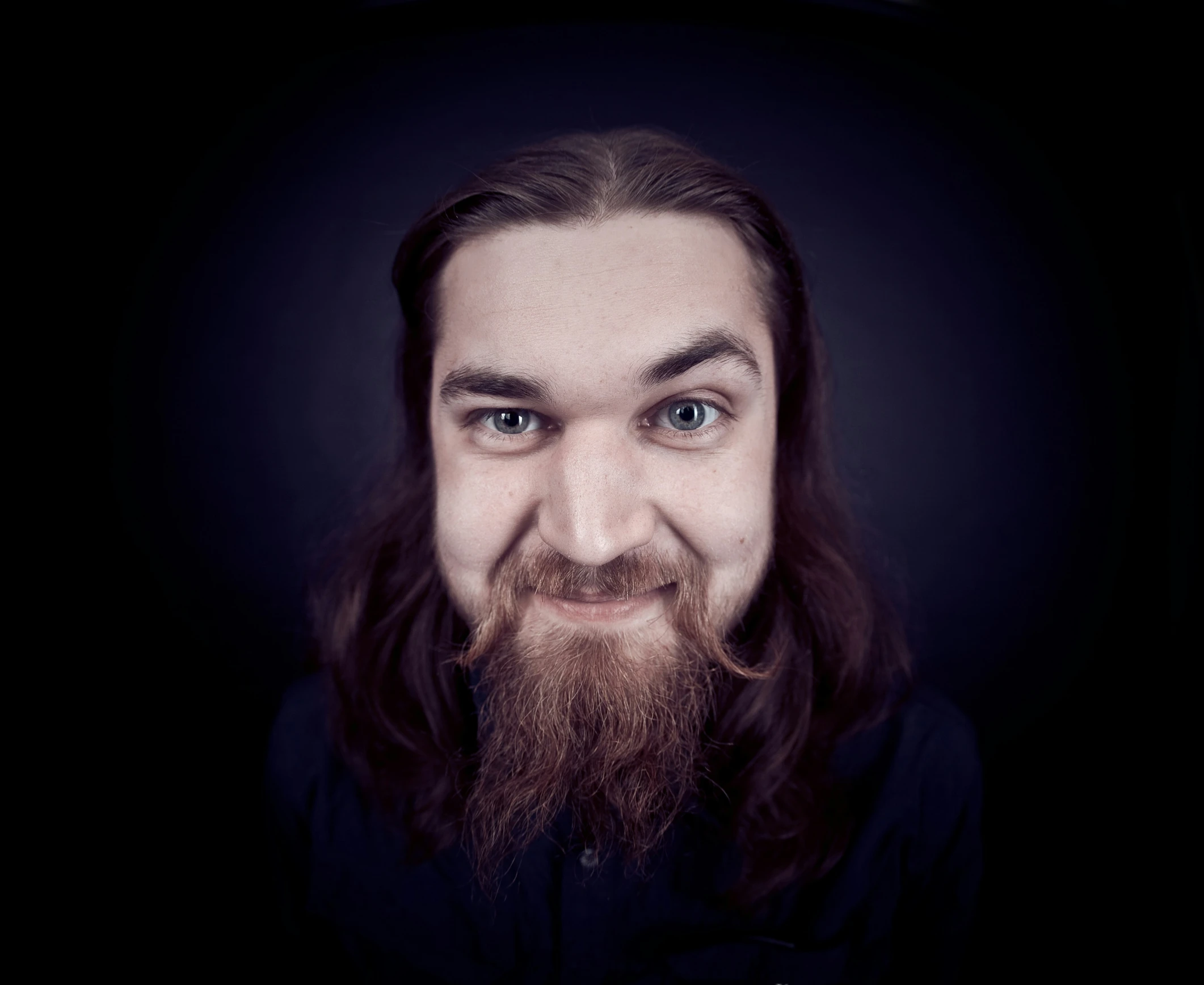 man with long hair and beard smiling at camera