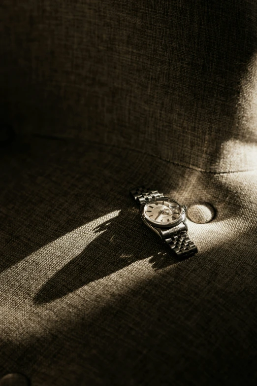 a small watch laying on the ground near its shadow