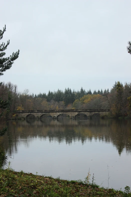 a bridge crossing over a large lake with an over cast sky