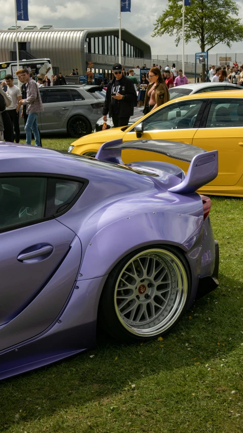 a purple colored car parked in a row on top of grass