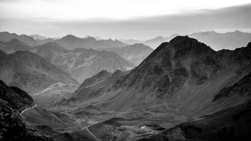 a black and white po of a river below a mountain range