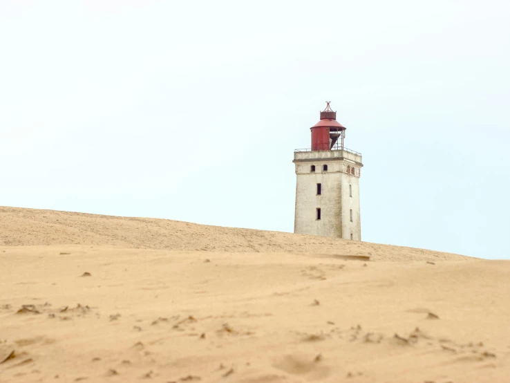 a white lighthouse in the desert under a blue sky