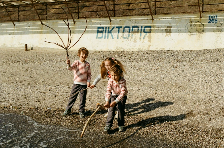 two young children stand on rocky ground near a building