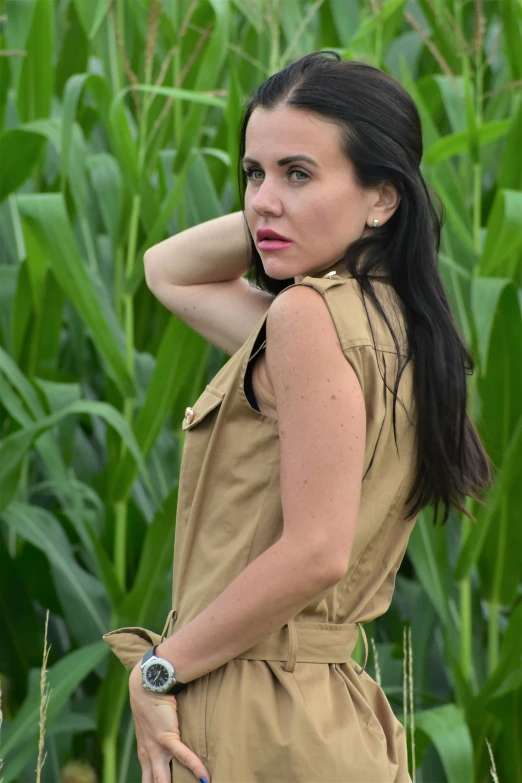 a woman is standing outside with her hands behind her neck