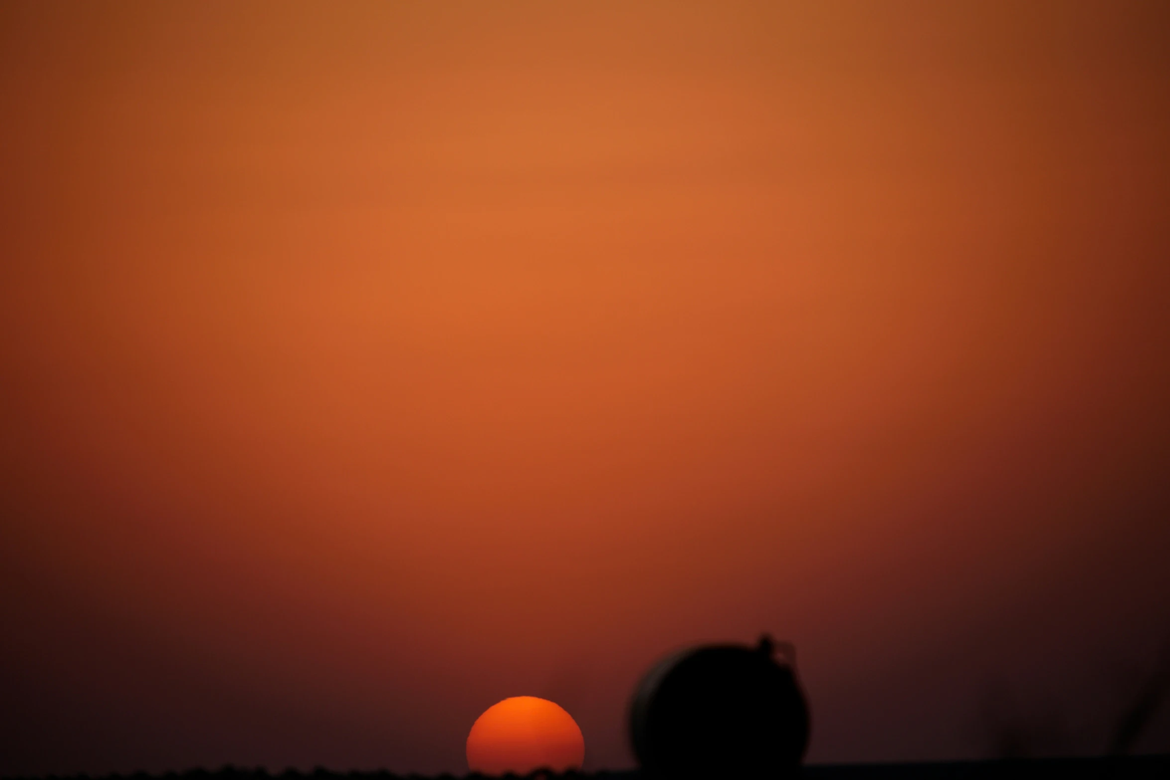 the sun is rising over a black and orange background