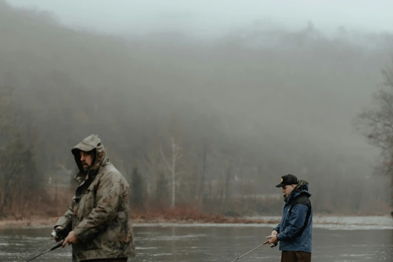 two men standing in water while holding fishing poles