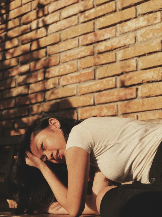 a woman laying on the ground next to a brick wall