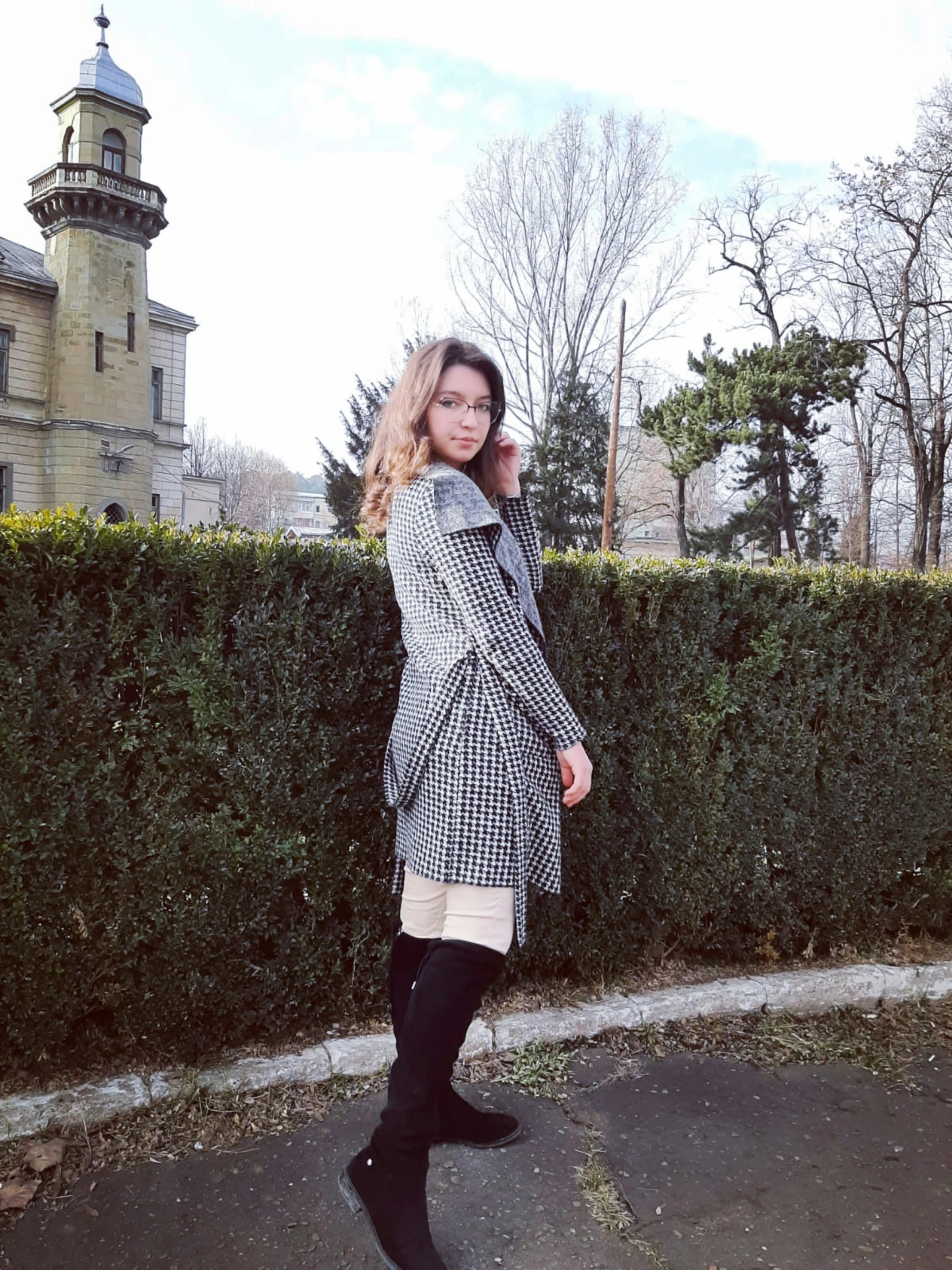 a woman standing near a fence with her arms around her neck